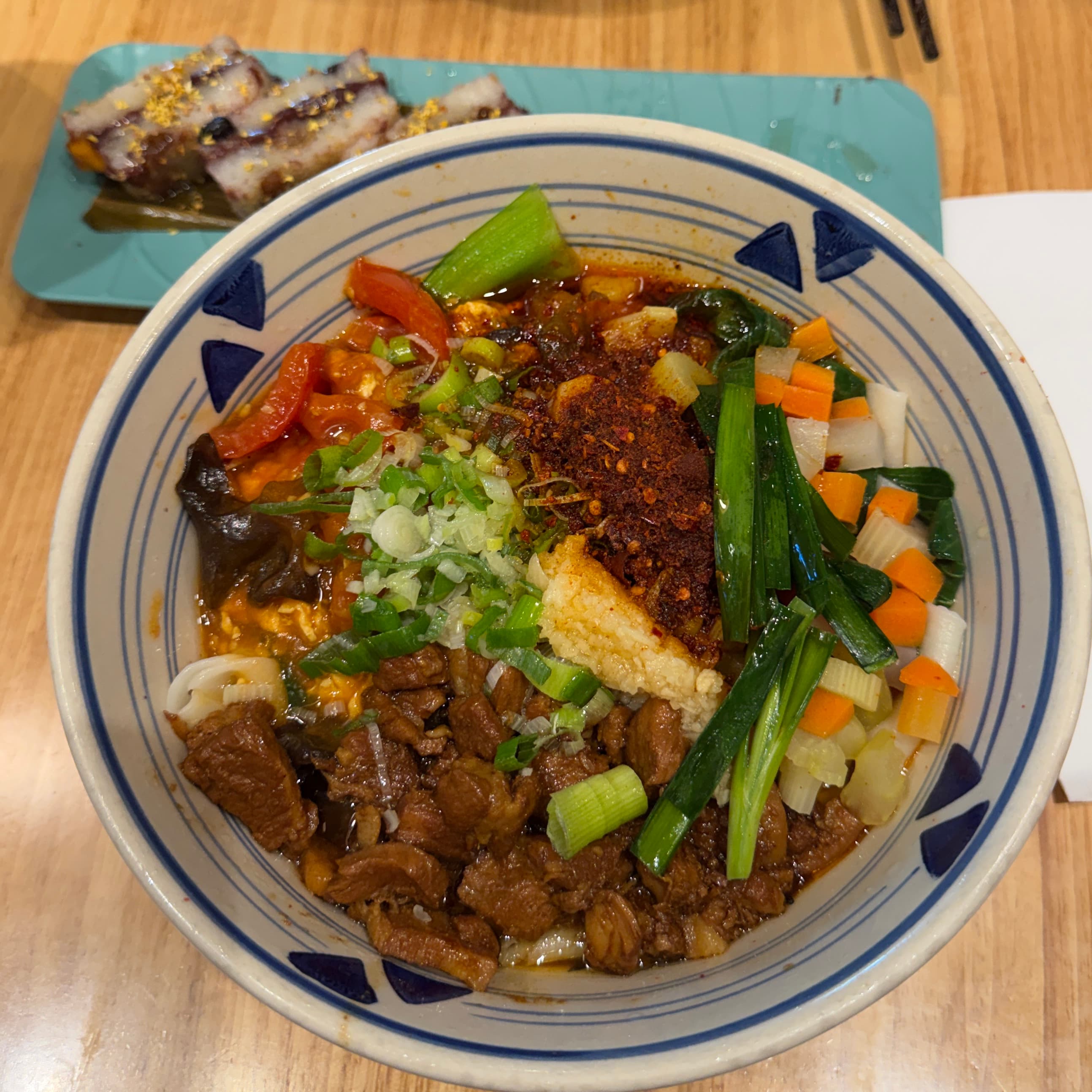 A colorful bowl of noodles, vegetables, and chili